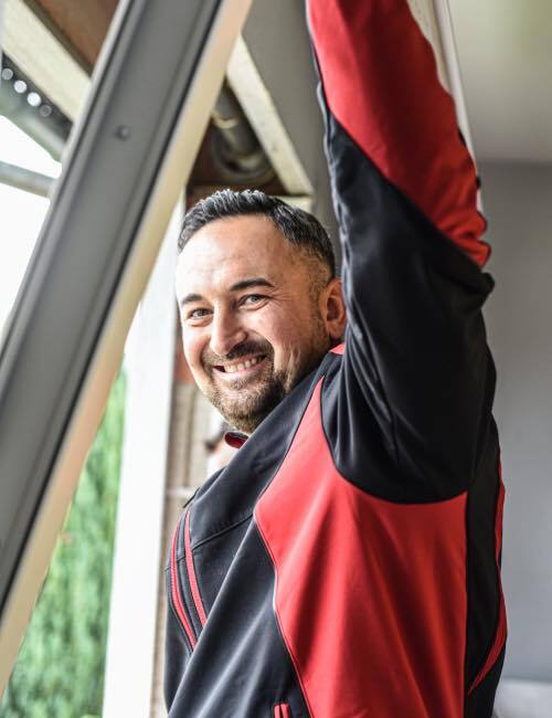 Ein Monteur von Fensterbau Hartmann der eine Wartung von einem Fenster macht.