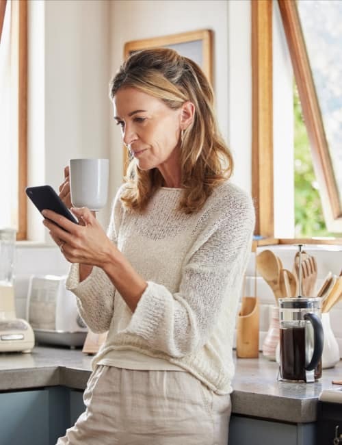 Eine Person mit Kaffeetasse, die sich über Förderung für Fenster informiert.